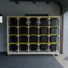 the shelves are filled with plastic containers and yellow tape on them, as well as black bins