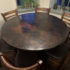 a table with four chairs around it and a potted plant in the window sill