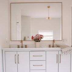 a bathroom vanity with two sinks and a large mirror over the sink that has flowers on it