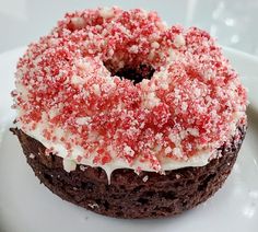 a chocolate cake with white frosting and sprinkles on top is sitting on a plate