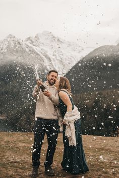 a man and woman standing in the snow with their arms around each other as they kiss