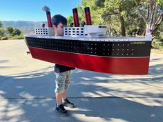 a boy is holding a model of a cruise ship