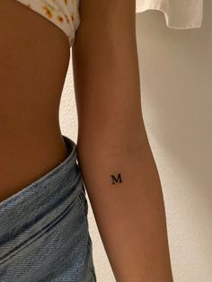 a woman's lower arm with the letter m tattooed on her left side, in black ink