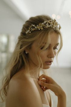 a woman wearing a gold headpiece with flowers on it's forehead and her hair pulled back