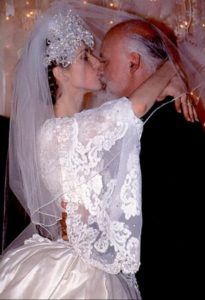 a bride and groom kissing in front of christmas lights