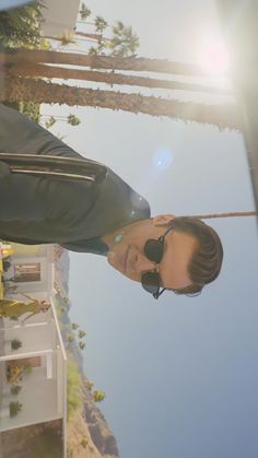 a man wearing sunglasses standing next to a palm tree