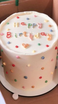 a birthday cake with white frosting and multicolored sprinkles in a box