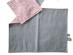 two napkins with pink and grey designs on them, one has a fork and spoon in it