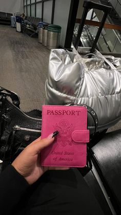 a pink passport sitting on top of a black bag next to a silver handbag