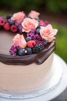 a chocolate cake with berries and flowers on top