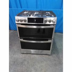 two ovens side by side in a room with a blue wall behind them and one on the floor