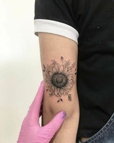 a woman's arm with a sunflower tattoo on the left side of her arm