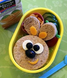 a bento box with some food in it and a spoon next to it on a table