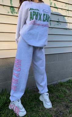 a woman standing in front of a house wearing sweatpants and sneakers with the words apx east printed on them