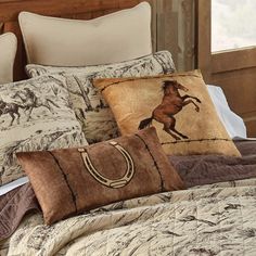 a bed topped with pillows and blankets covered in horses