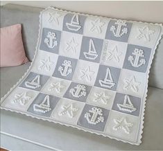 a crocheted blanket with sailboats and anchors on it sitting on a couch