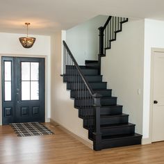 a black stair case next to a white door