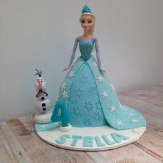 a frozen princess cake with a snowman next to it