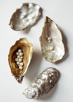 three seashells with pearls in them on a white surface