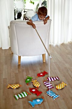 a little boy playing with toys on the floor in front of a white chair and window