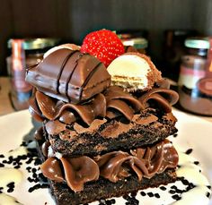 three chocolate desserts stacked on top of each other with strawberries in the background