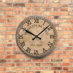 a large clock mounted to the side of a brick wall with roman numerals