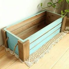 a wooden crate sitting on top of a floor next to a potted planter