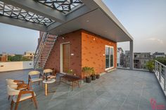 a balcony with chairs, tables and stairs leading up to the roof top terrace area