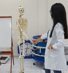 a woman in a lab coat standing next to a skeleton