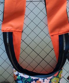 an orange and blue purse sitting on top of a white tiled floor next to a wall