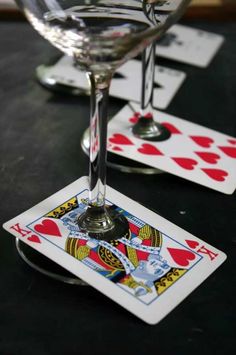 two wine glasses sitting next to each other on top of a table with playing cards