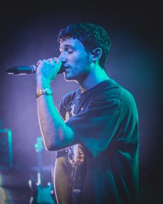 a young man singing into a microphone on stage