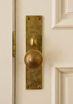 a door handle on a white door with gold knobs and an oval brass plate