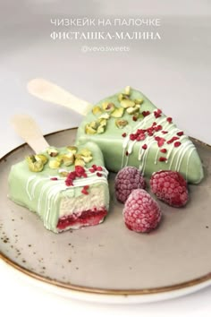 two pieces of cake on a plate with raspberries and pistachios