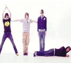 three young men standing in front of a white background with their arms up and one laying on the ground