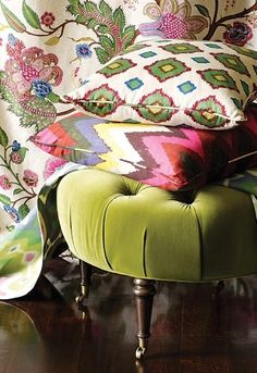 a green ottoman sitting on top of a hard wood floor next to a window covered in curtains