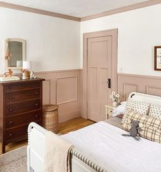 a white bed sitting in a bedroom next to a wooden dresser and chest of drawers