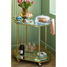 a gold serving cart filled with champagne and cakes