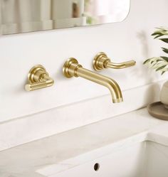 two brass faucets on a white bathroom sink