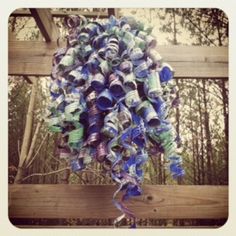 a bunch of blue and green glass bottles hanging from a wooden fence with trees in the background