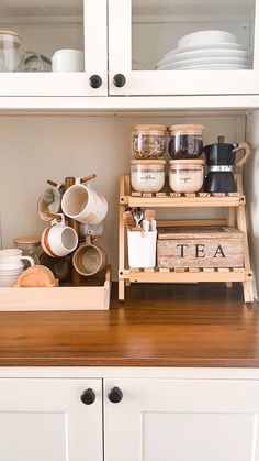 the coffee and tea corner is organized with wooden trays, dishes, cups, and utensils