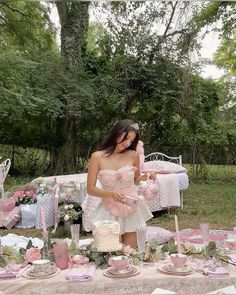 a woman standing in front of a table filled with pink and white dishes, cups and saucers