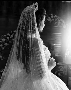 a woman in a wedding dress and veil is looking at the light from behind her