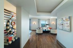 a living room filled with lots of furniture next to a painting on the wall and wooden floors