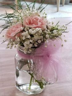 pink and white flowers in a mason jar on a dining room table with purple ribbon