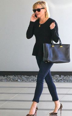 a woman walking through an airport talking on her cell phone and carrying a black bag