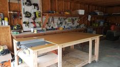 a workbench in a garage with tools on the table and shelves above it