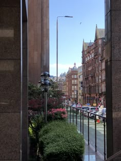 the view from an outside balcony looking down at buildings and street lamps on either side