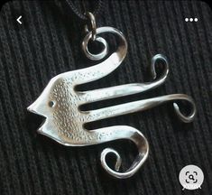 a silver necklace with two birds on it's sides and swirls in the middle