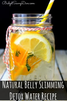 a jar filled with lemons and water on top of a wooden table